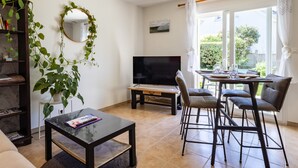 Un salon avec un téléviseur, une table à manger avec des chaises, un canapé et une bibliothèque.