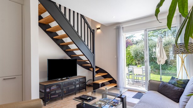 Ein modernes Wohnzimmer mit einem Glastisch, einer Couch, einem Fernseher und einer Treppe.
