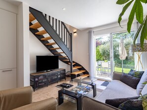 A modern living room with a glass coffee table, a sofa, a TV, and a staircase. - Holiday Home 'Gite Kerstephan' with Private Terrace, Private Garden and Wi-Fi (Perros-Guirec)