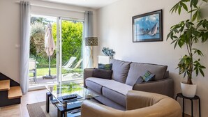 Ein modernes Wohnzimmer mit einer Couch, einem Couchtisch und einer großen Küstertopf-Pflanze.
