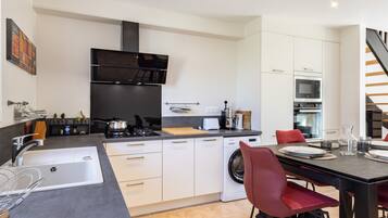 A modern kitchen with a stove, sink, and dining area with chairs.