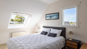 Ein Schlafzimmer mit einem Bett, zwei Nachttischen, einem Fenster und einem Bild an der Wand.