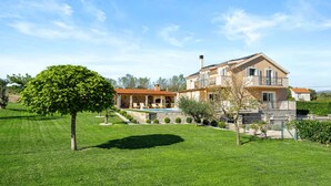Ein zweistöckiges Haus mit Steinfassade, einem Swimmingpool und einem gepflegten Rasen.