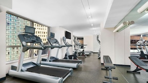 Un gimnasio con cintas de correr, una banca y equipo de pesas.