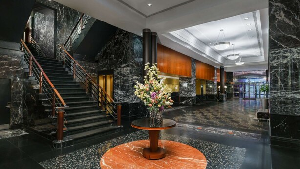 Un vestíbulo con una escalera de mármol, mostrador de recepción y un arreglo floral.