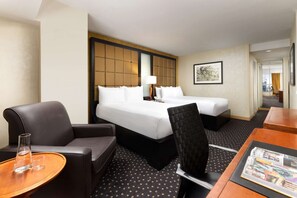 Ein Hotelzimmer mit zwei Betten, einem Sofa, einem Esstisch und einem Stuhl.