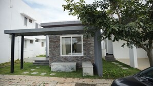 Une maison moderne avec une façade en pierre, un porche abrité et une voiture garée devant.