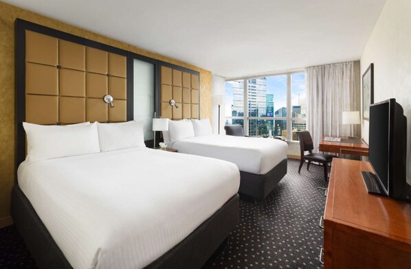 A hotel room with two beds, a desk, a chair, a TV, and a large window with a city view. - Premier Paradise | Rockefeller l Ball Drop view (New York)
