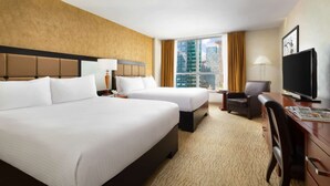 A hotel room with two beds, a desk with a television, and a view of a cityscape. - Double Deluxe | Times Square l City View (New York)