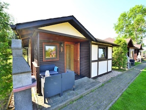 A cabin with a covered porch, outdoor seating, and a stone pillar. - Comfortable Holiday Homes, Jacuzzi, Summer Pool (Postomino)
