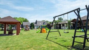 A playground with swings and a covered seating area. - Comfortable Holiday Homes, Jacuzzi, Summer Pool (Postomino)