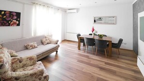 Ein Wohnzimmer mit einer Couch, einem Esstisch mit Stühlen, einer Heizung und einer Wand-Klimaanlage.