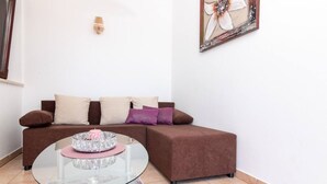 A living room with a brown sectional sofa, a glass coffee table, and a framed artwork on the wall. - Apartman FLORIS with AC and WIFI (Punat)