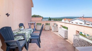 A balcony with a table and chairs, a small table, and planters. - Apartman FLORIS with AC and WIFI (Punat)