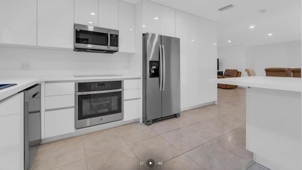 Una cocina moderna con armarios blancos, electrodomésticos de acero inoxidable y una isla central.