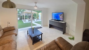 Una sala de estar moderna con un sofá, una mesa de centro y un televisor sobre un mueble.