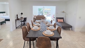 Un comedor moderno con una mesa rectangular dispuesta para cuatro personas, rodeada por seis sillas.