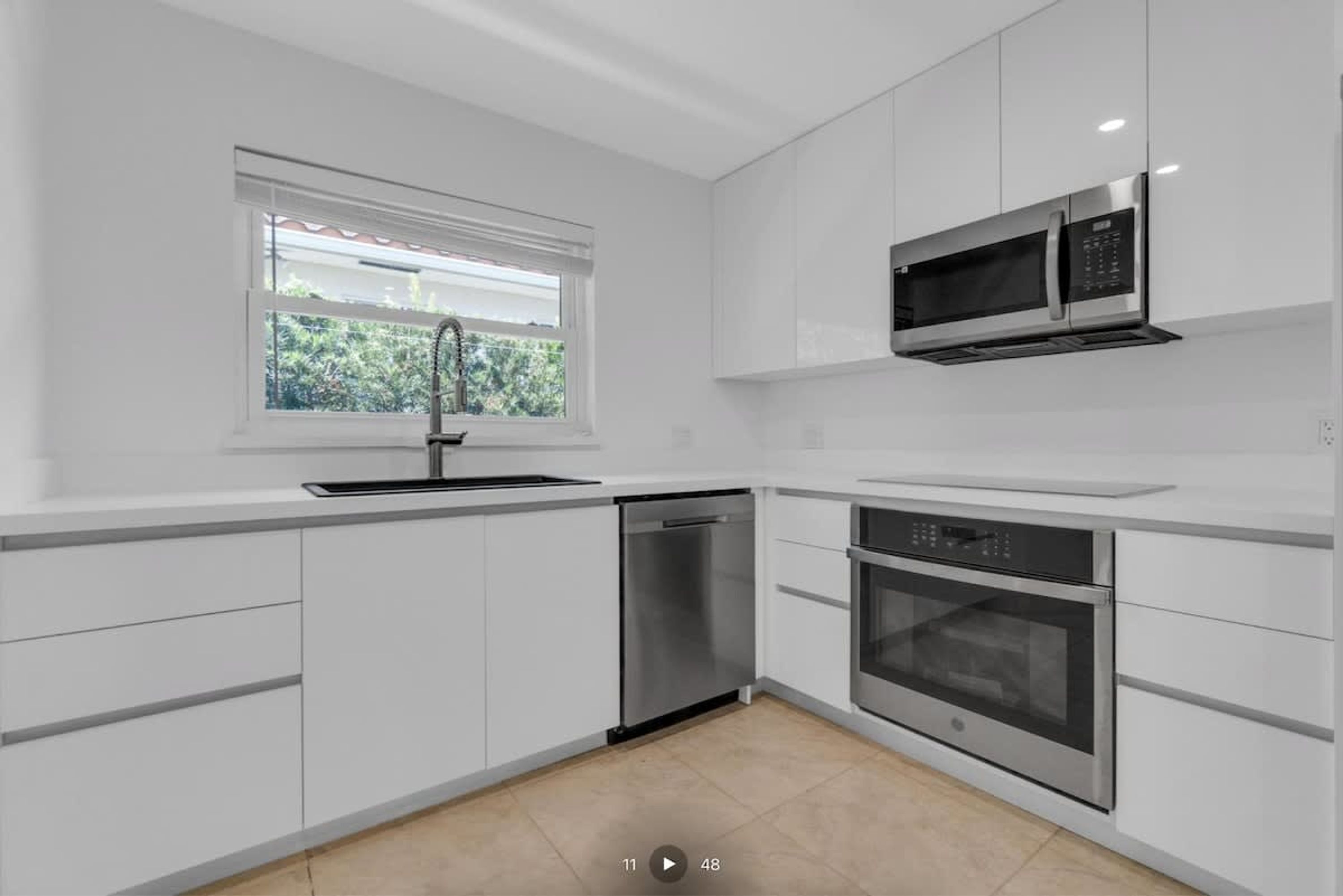 A modern kitchen with white cabinetry, a dishwasher, a built-in oven, and a microwave.