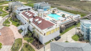 Ett semesterhotell med en stor pool, flera byggnader och utsikt över stranden.