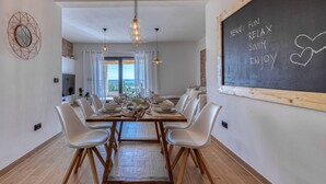 A dining area with a large table set for six, white chairs, pendant lights, and a chalkboard menu on the wall. - Villa La Vrana Zadarvillas (Pakostane)
