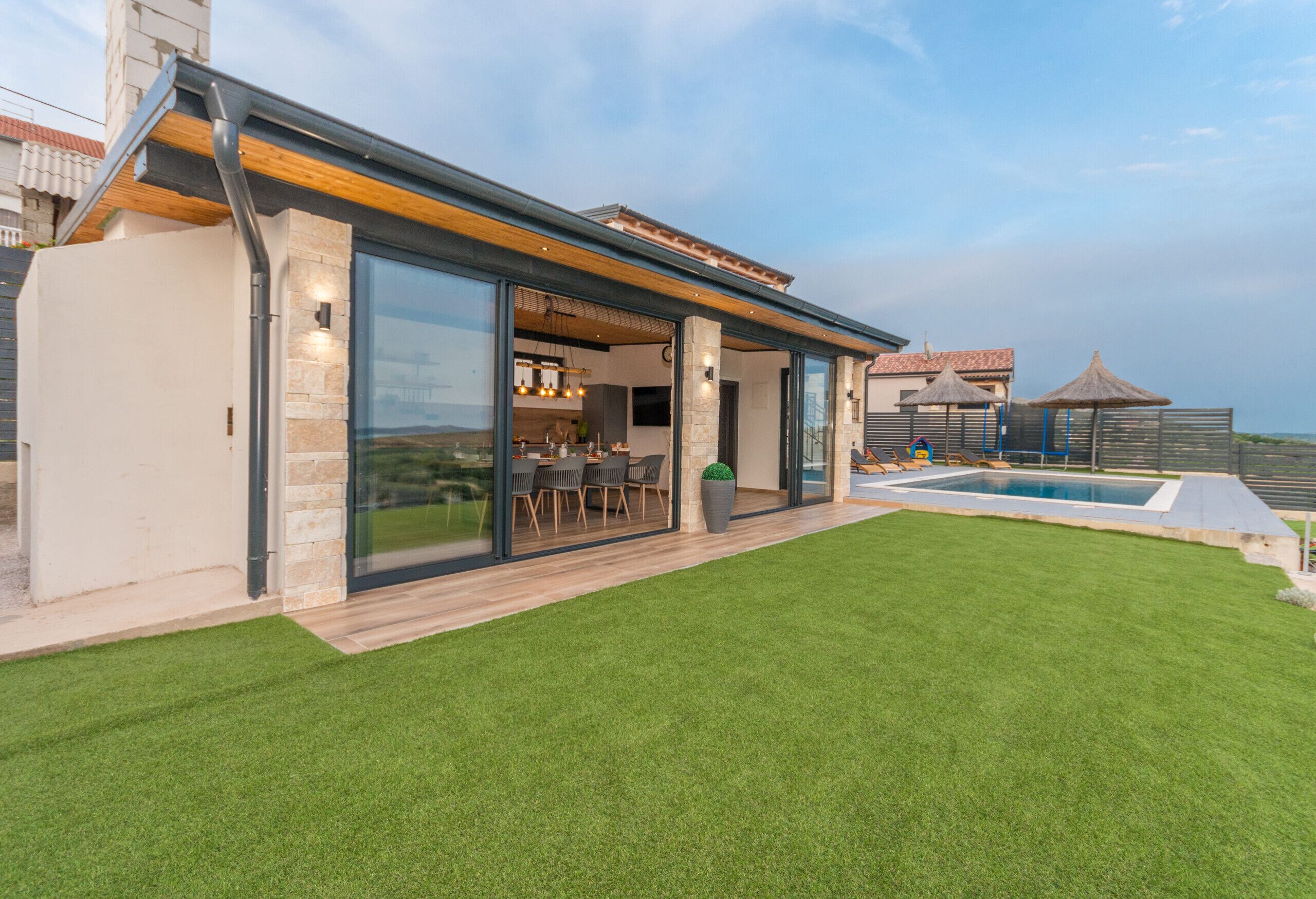 A modern house with a swimming pool, a patio, and a well-maintained lawn.