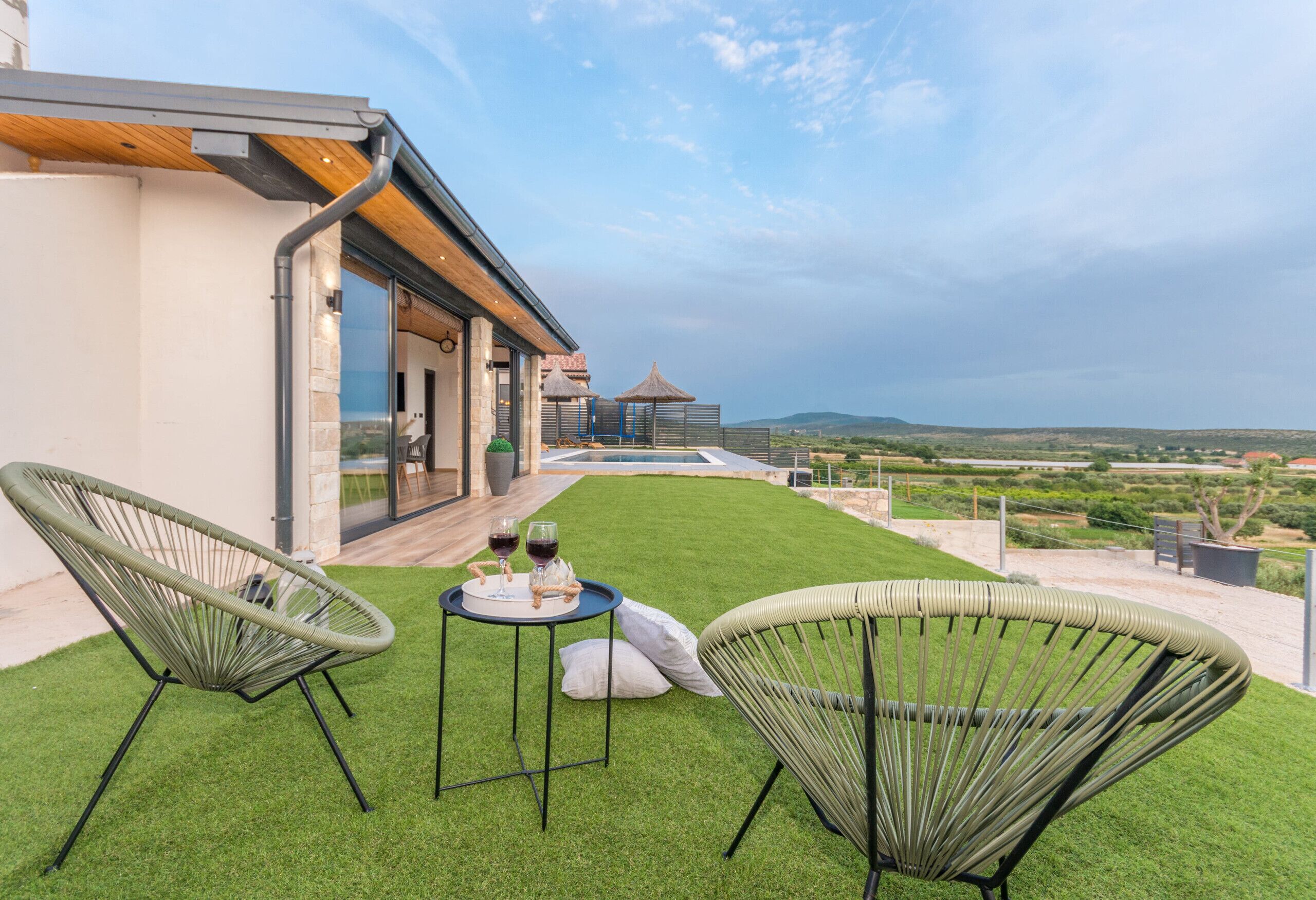 Eine Terrasse mit zwei Korbstühlen, einem kleinen Tisch mit Getränken und Blick auf die Landschaft.