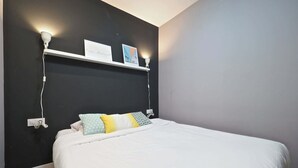 A bedroom with a bed, a shelf with two framed pictures, and a wall-mounted light fixture. - Torrassa Cozy Apartment by Olala Homes (L'Hospitalet de Llobregat)