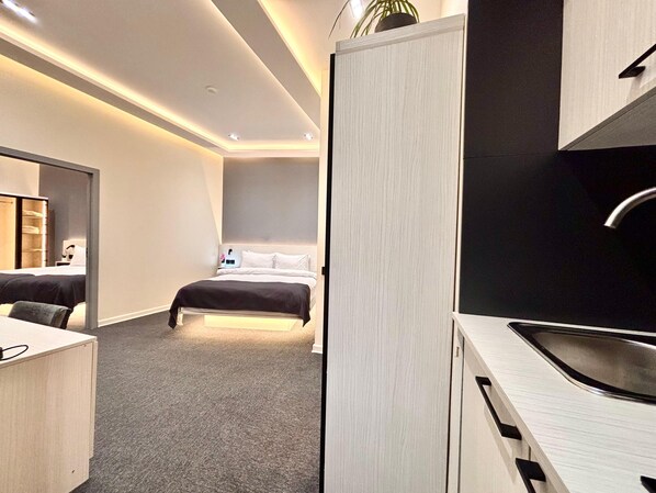 A modern hotel room with a bed, a desk, a mirror, and a kitchenette. - JM Central Boutique Hotel (Baku)