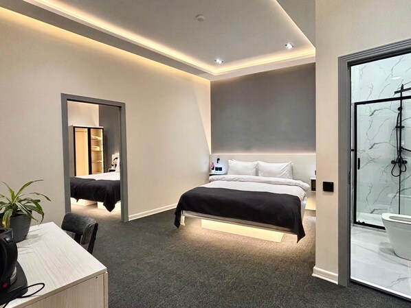 Ein modernes Hotelzimmer mit einem großen Bett, einem Schreibtisch mit Stuhl, einer Dusche und einem Spiegel.