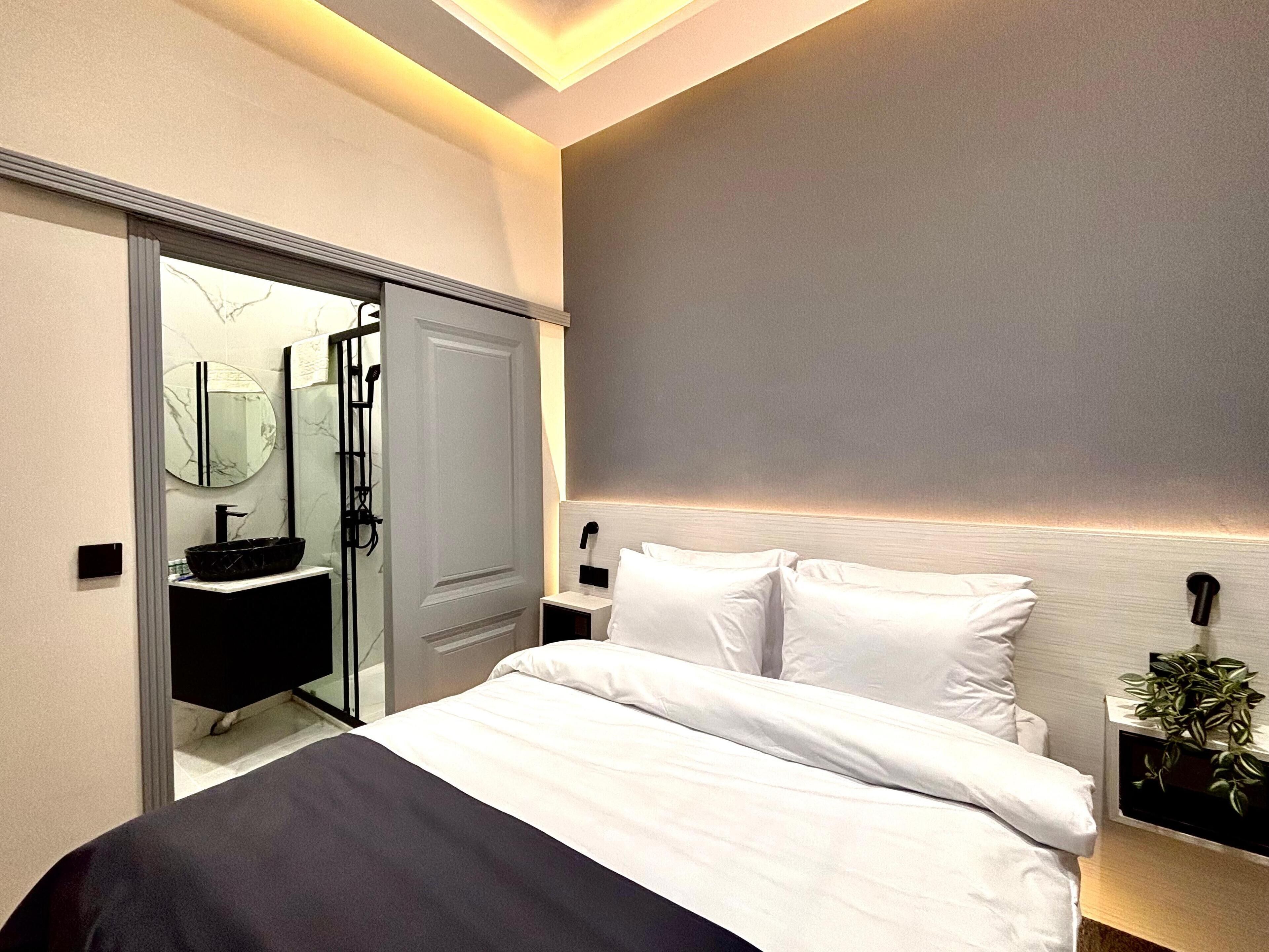 A modern bedroom with a bed, bedside table, and a nightstand with a plant.