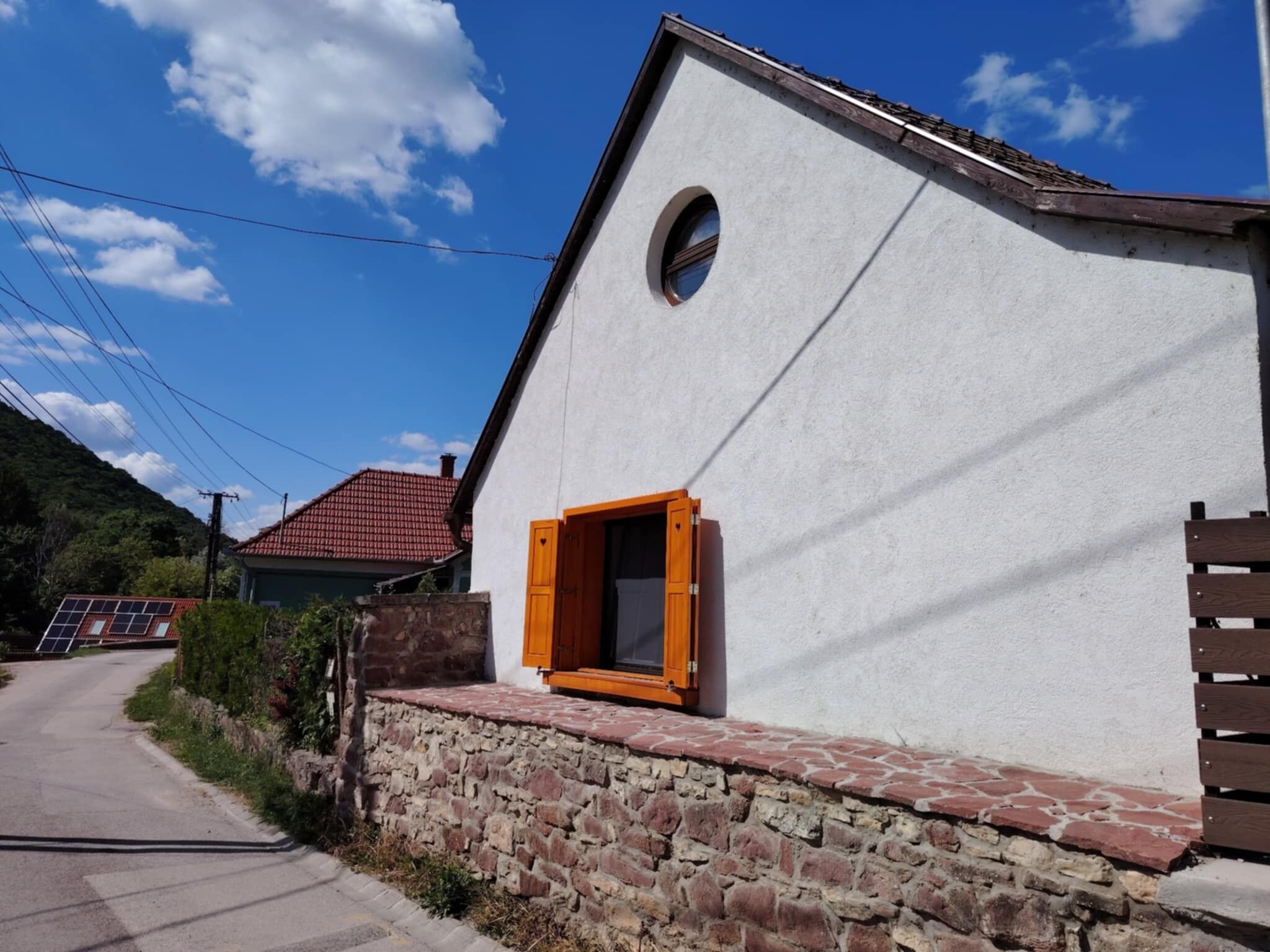 Un bâtiment blanc, avec un socle en pierre et un toit recouvert de tuiles rouges.
