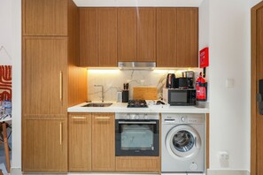 Una cucina funzionale con mobili in legno, forno a incasso, lavatrice e microonde.