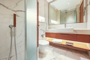 A modern bathroom with a glass shower enclosure, a white toilet, a vanity with a mirror, and marble flooring. - Bloomfields Fantastic Stu in Azizi (Dubai)