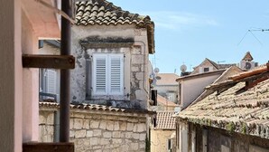 Eine enge Straße mit Steinhäusern, einem sichtbaren Fenster mit Fensterläden und einem Ziegeldach.