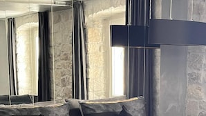 Una habitación de hotel moderna con una cama grande, ropa de cama oscura y una pared de acento de piedra.