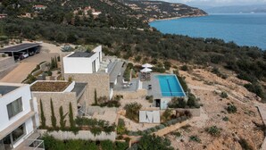 A modern villa with a rooftop pool, terraced garden, and a view of the sea.