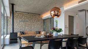 A modern dining area with a stone wall, a wooden table, black chairs, and a large pendant light.