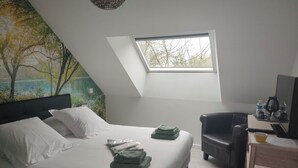 Quarto com cama, escrivaninha, cadeira e claraboia.