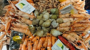 Prato de frutos do mar com diversos tipos de mariscos e camarões, incluindo lagostas e amêijoas, disposto sobre uma base de papel branco.