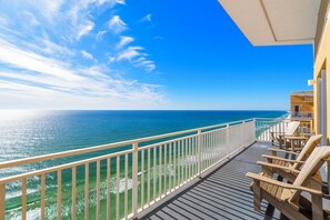 A balcony with a view of the ocean, wooden chairs, and a railing. - Condo In The Clouds-King Beds-Beachfront Resort (Panama City Beach)