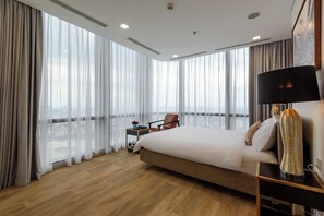 Ein Hotelzimmer mit einem großen Bett, einem Sessel, einem kleinen Tisch und einer Lampe.