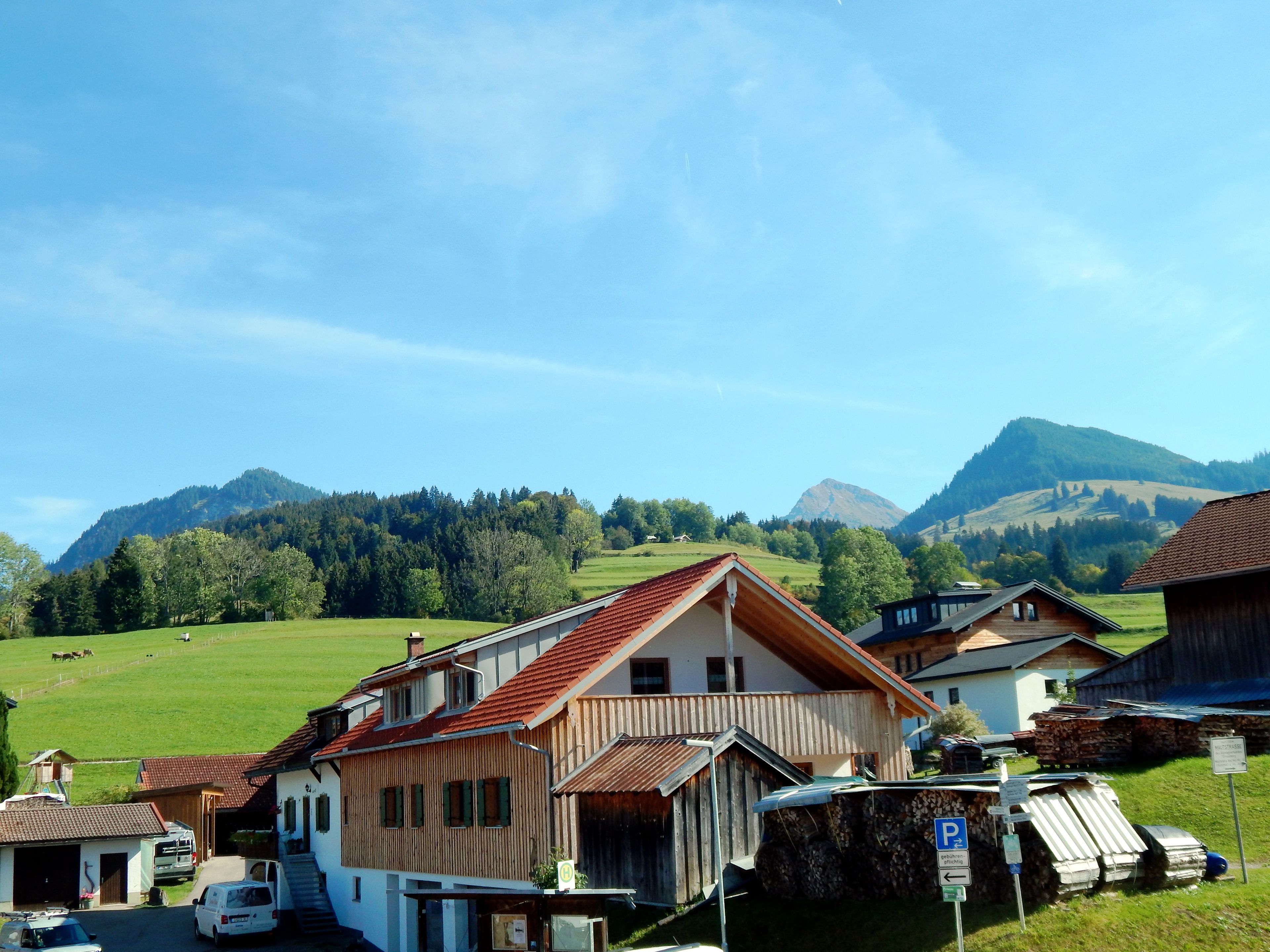 Ein ländliches Dorf mit traditionellen Holzhäusern, blauem Himmel und einer bergigen Kulisse.