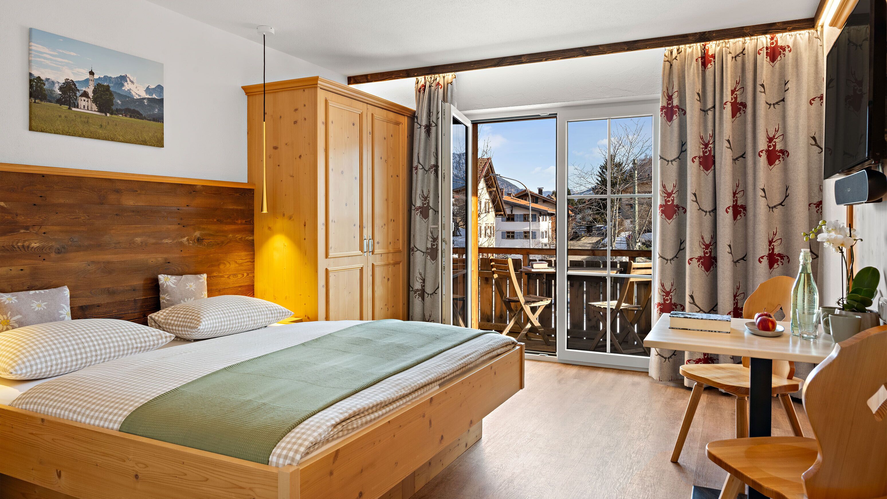 Une chambre avec un lit en bois, une vue sur un balcon et un coin repas comprenant une table et des chaises.