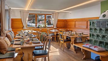 Un comedor acogedor con mobiliario de madera, un ventanal con cortinas y vistas al exterior.