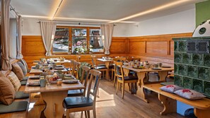 Un coin repas accueillant, avec des meubles en bois, une grande fenêtre agrémentée de rideaux et une vue sur l’extérieur.