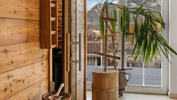 Un interior de madera con un banco, una bañera de madera y una planta en maceta.