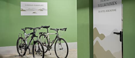 Een fietsenstalling met twee fietsen en een bord waarop 'Fahrrad-Parkplatz' en 'Hotel Bergsonne' staat.