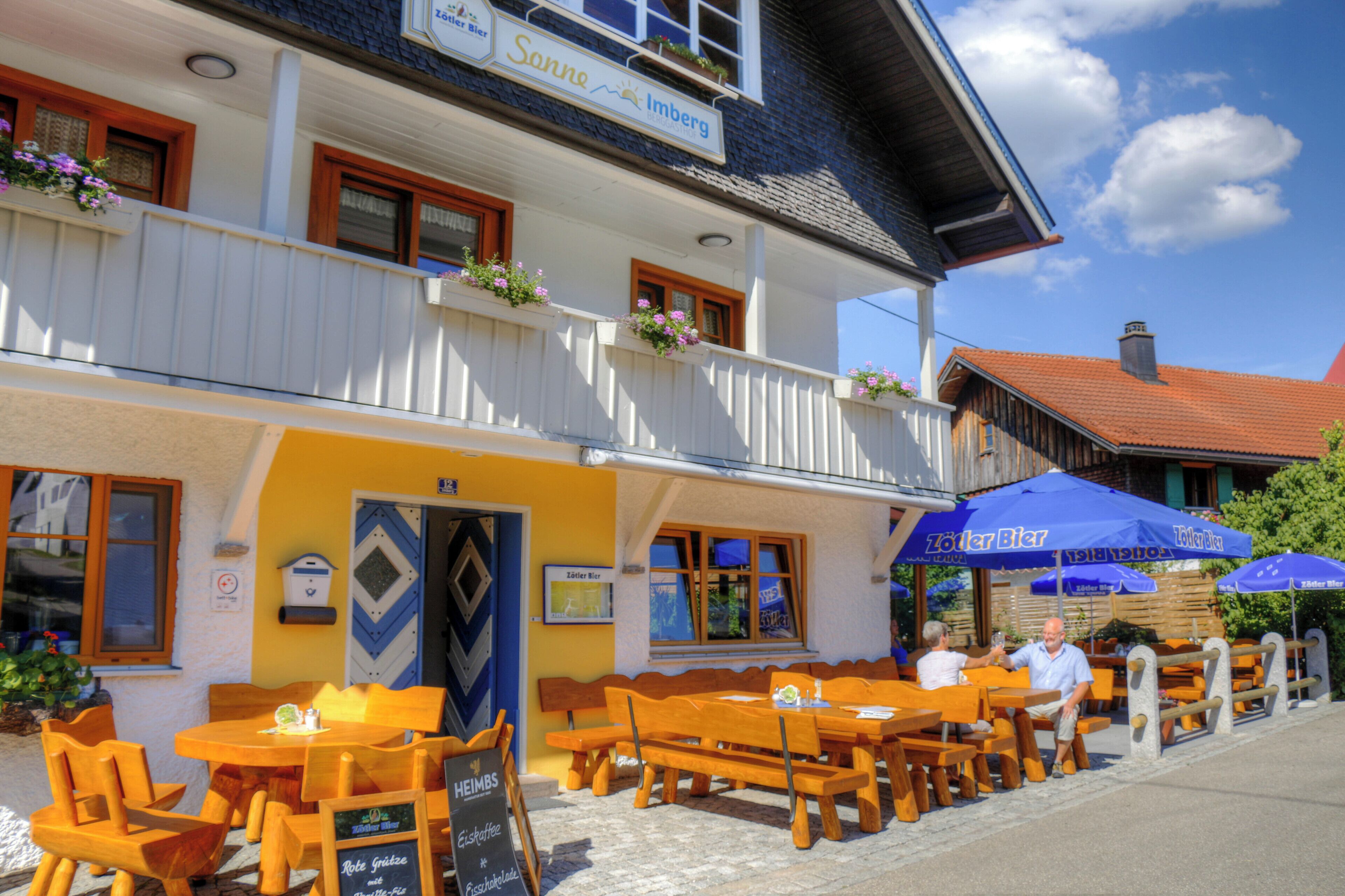 Un restaurant doté d’une terrasse, de tables et de bancs en bois, et d’une enseigne indiquant qu’il propose une cuisine régionale.
