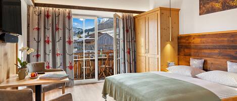 Habitación de hotel con cama, escritorio con silla, televisión y vistas a un paisaje montañoso.
