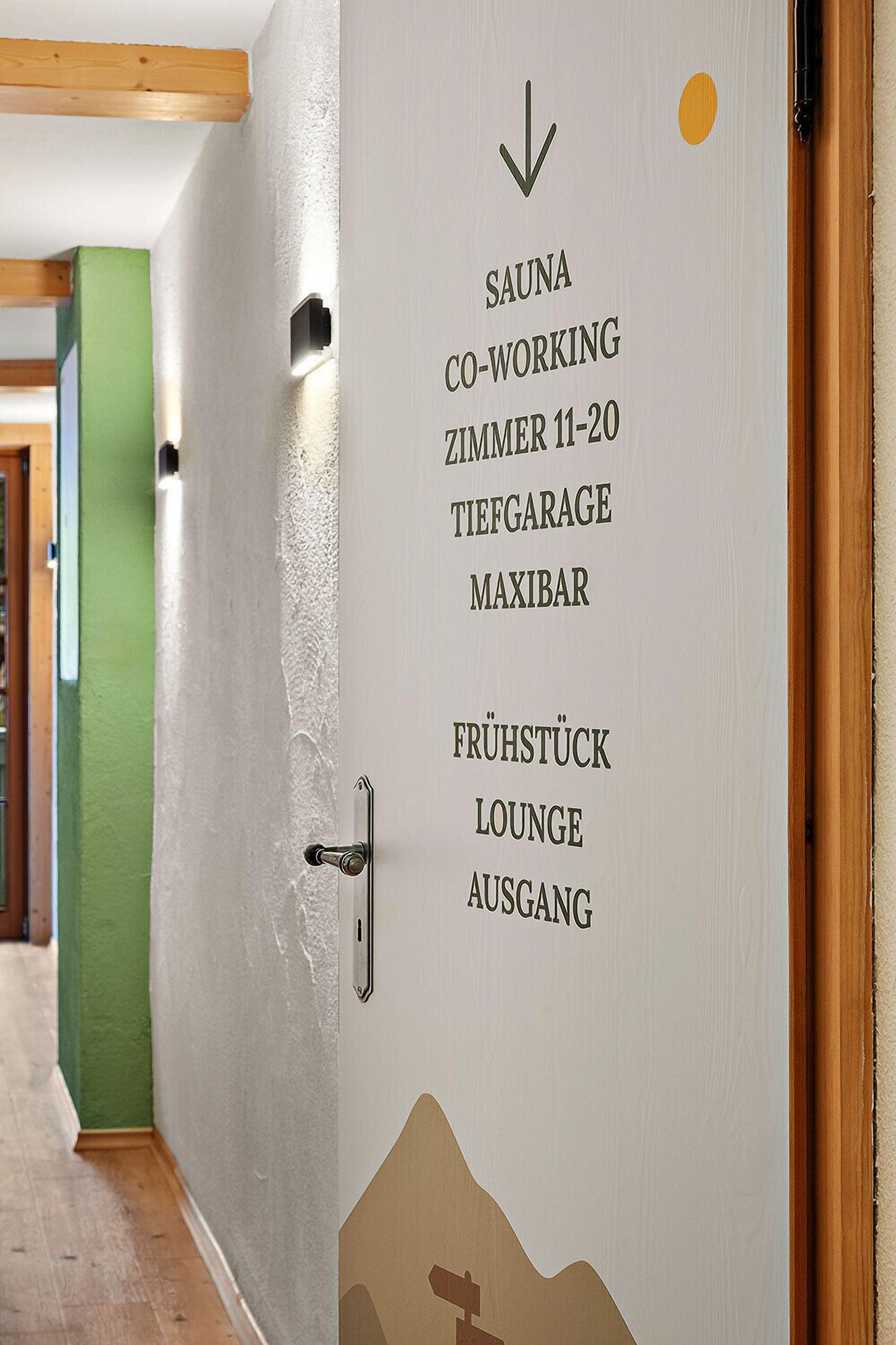 Een muur met pijlen en tekst die de locatie van diverse faciliteiten van het hotel aangeeft, zoals de sauna, een co-workingruimte en een lounge.